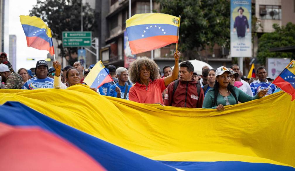 epaselect epa12627465 A person holds a Venezuelan flag during a march organized by Chavismo supporters, in Caracas, Venezuela, 04 January 2026. Hundreds of Chavismo supporters mobilized to demand that US President Donald Trump release Nicol