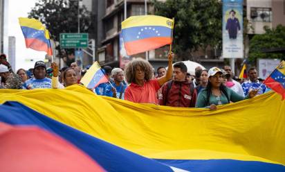 epaselect epa12627465 A person holds a Venezuelan flag during a march organized by Chavismo supporters, in Caracas, Venezuela, 04 January 2026. Hundreds of Chavismo supporters mobilized to demand that US President Donald Trump release Nicol