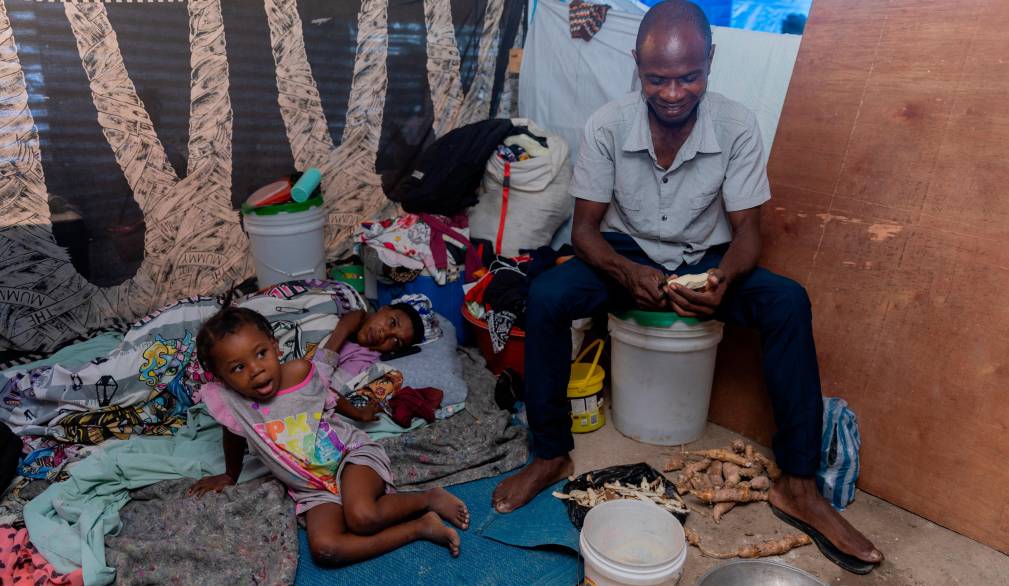 Un padre di famiglia sbuccia della manioca per nutrire le figlie, in un centro per sfollati, a Port-au-Prince. Foto Unicef