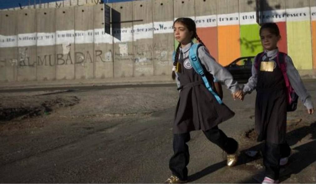 Una bambina e un bambino davanti al muro costruito dal Governo israeliano in Cisgiordania. Per gentile concessione di WeWorld ed Azione contro la fame