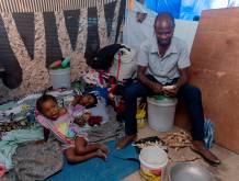 Un padre di famiglia sbuccia della manioca per nutrire le figlie, in un centro per sfollati, a Port-au-Prince. Foto Unicef