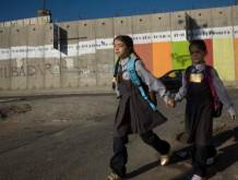 Una bambina e un bambino davanti al muro costruito dal Governo israeliano in Cisgiordania. Per gentile concessione di WeWorld ed Azione contro la fame