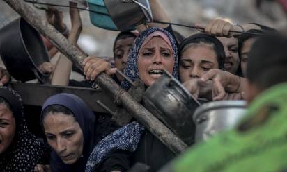 GAZA CITY, GAZA - JULY 23: Palestinians carrying pans, gather to receive hot meals, distributed by a charity organization in Gaza City - SAEED M. M. T. JARAS / Anadolu via AFP